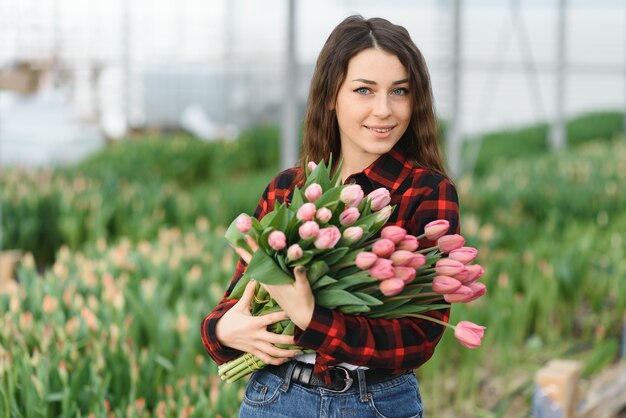 Chica, trabajadora con flores en invernadero