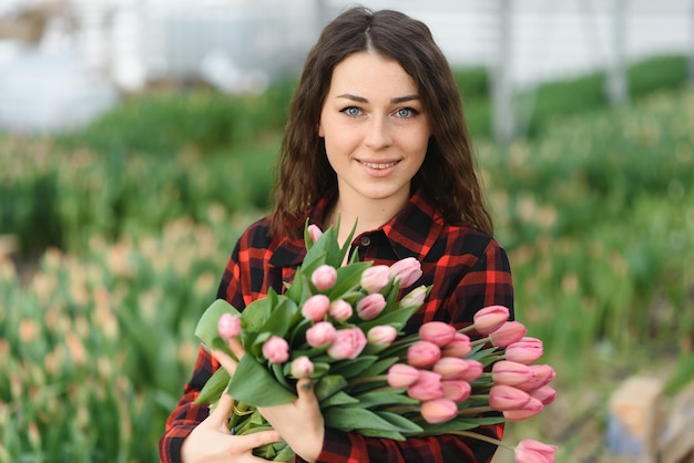 Chica, trabajadora con flores en invernadero