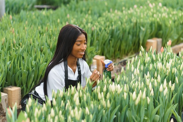 Chica, trabajadora con flores en invernadero