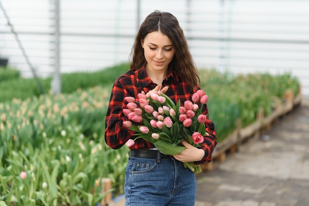 Chica, trabajadora con flores en invernadero