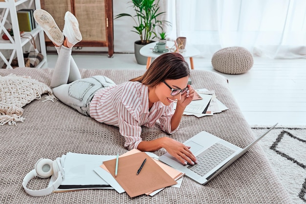 Chica trabajando en casa mujer escribiendo en la computadora portátil en la cama Autoaislamiento