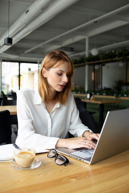 Chica trabajando en una laptop en un café