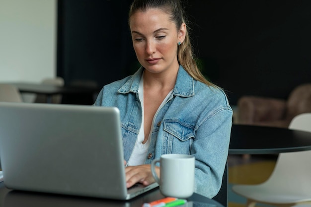 Chica trabajando en una laptop en una cafetería de moda foto de archivo