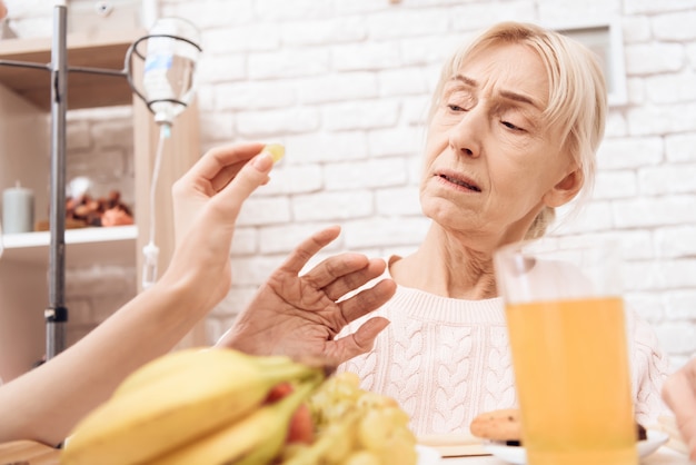 Chica trae el desayuno en la bandeja. La mujer se niega a comer.