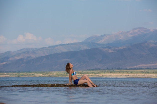 Chica en traje de baño en un lago de montaña