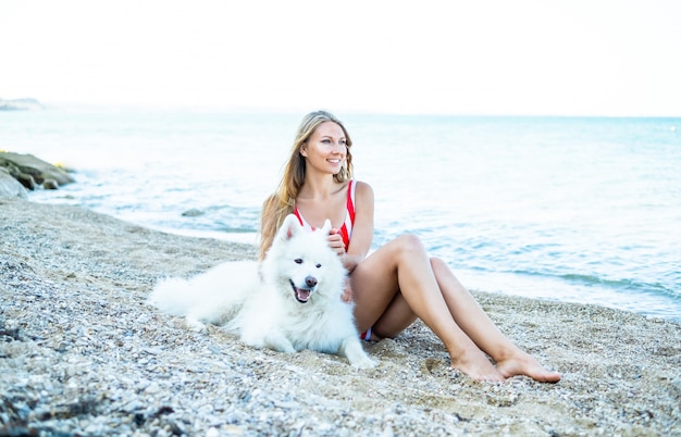 Chica en traje de baño con un perro en la playa