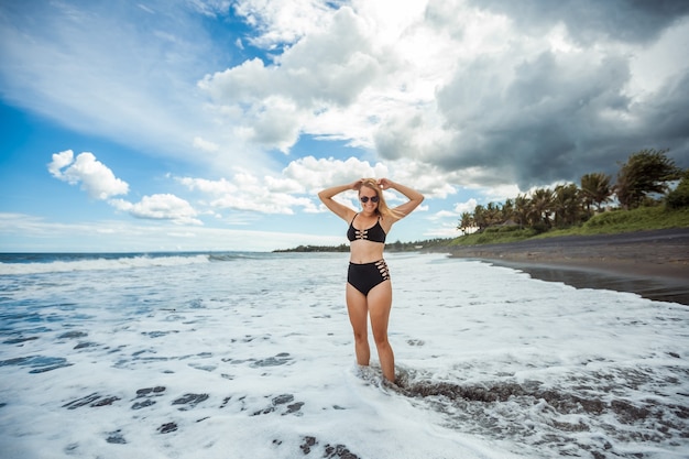 Chica en traje de baño de pie en la ola del mar