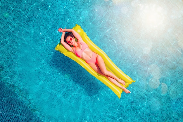 Chica en traje de baño que se broncea en una piscina