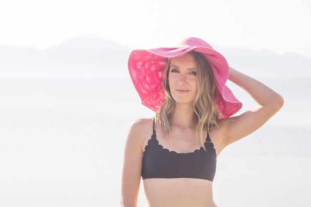 Chica en traje de baño y un sombrero junto al mar.