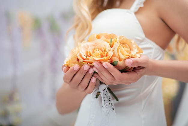 Una chica con un traje blanco y una bata sexy con un ramo de rosas, manos grandes, romance y decoración.