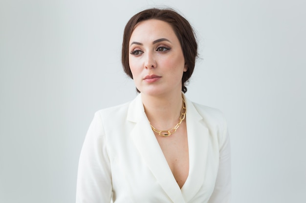 Chica en traje blanco con maquillaje posando en una habitación blanca. Retrato de estudio de longitud de cuerpo de estilo de moda