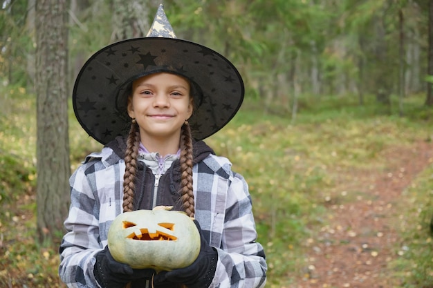 Chica en traje de bruja con linterna de calabaza concepto de halloween chica en el bosque jugando con jack linterna