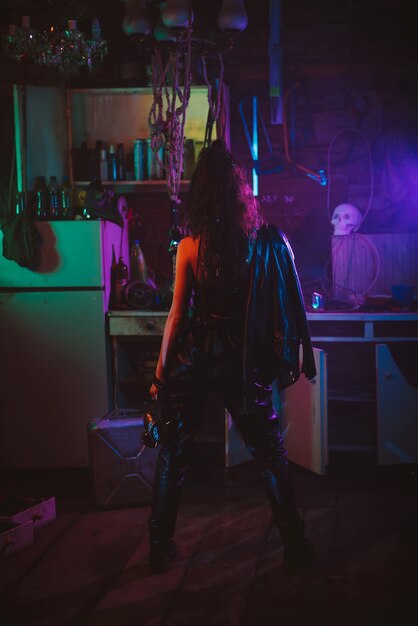 Chica con un traje cyberpunk con una luz de neón en el garaje. Cosplay Steampunk en el estilo post-apocalíptico del futuro