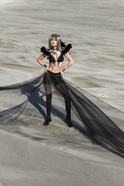 Chica en traje de festival creativo posando en el desierto