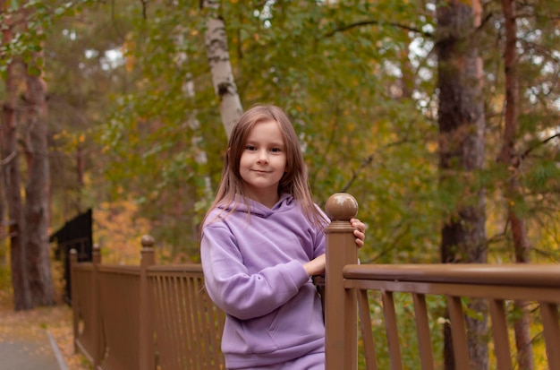 Una chica con traje morado y cabello largo inhala aire fresco en otoño en el bosque El concepto de respirar inhalar relajarse