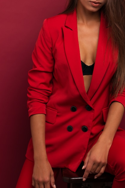 Chica en un traje rojo con una hermosa prensa sobre el estómago. Estudio de fondo de Borgoña.