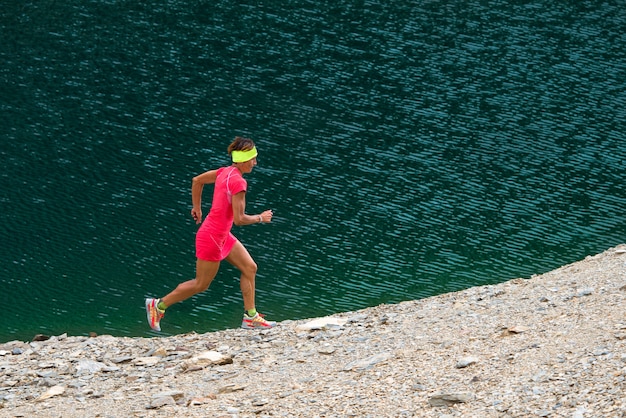 Chica con traje rosa corre cerca de un lago