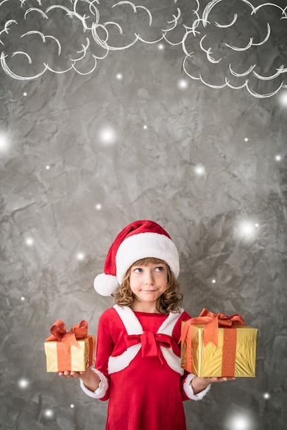 Chica en traje de santa con cajas de regalo