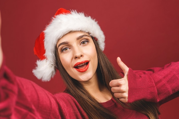 Chica en traje de Santa sonriendo y tomando selfie en teléfono móvil