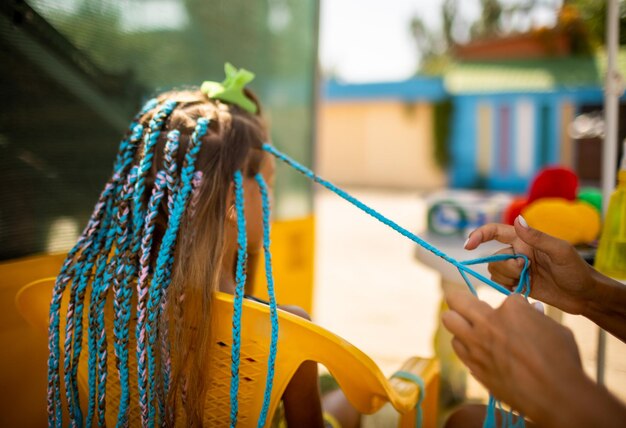 Una chica con traje teje trenzas africanas en su cabello en un día soleado