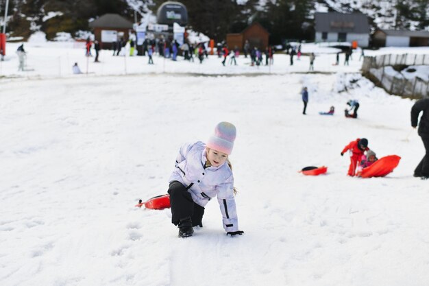 Una chica con trineo bob de nieve en la nieve.