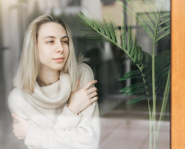 Chica triste cerca de la ventana pensando en algo