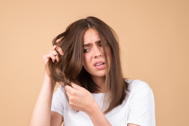 Chica triste mirando el cabello dañado el problema de la pérdida de cabello espacio de copia aislado