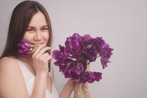 Chica con tulipanes sobre un fondo blanco.