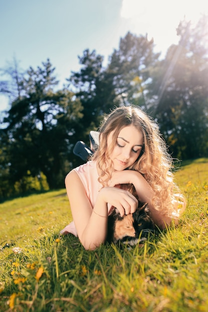 Foto chica tumbada en la hierba con gato. concepto de clima cálido de primavera o verano.