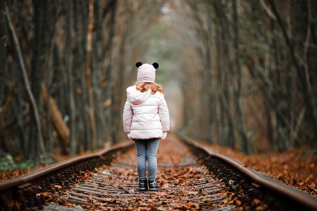 Chica en túnel verde de ferrocarril. túnel del amor en otoño. Ferrocarril y túnel de árboles