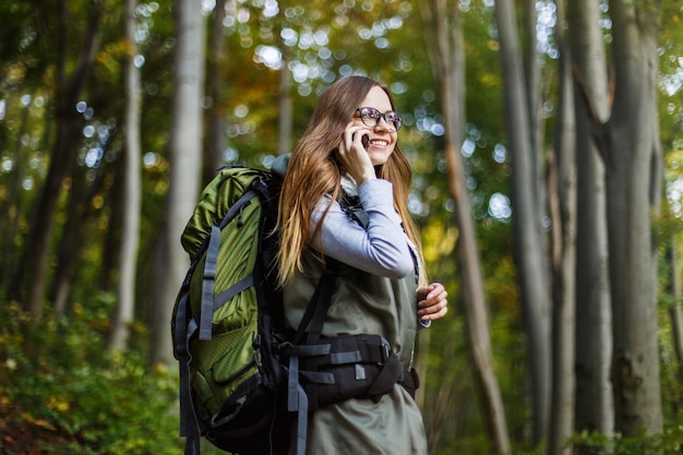 Chica turista en bosque con smartphone