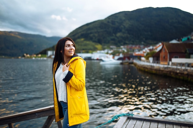 Chica turista en chaqueta amarilla posando en el lago en Noruega Mujer activa relajándose en Noruega