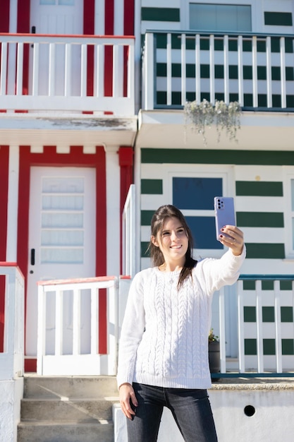 Chica turista haciéndose fotos con la decoración de las fachadas de las casas de Costa Nova