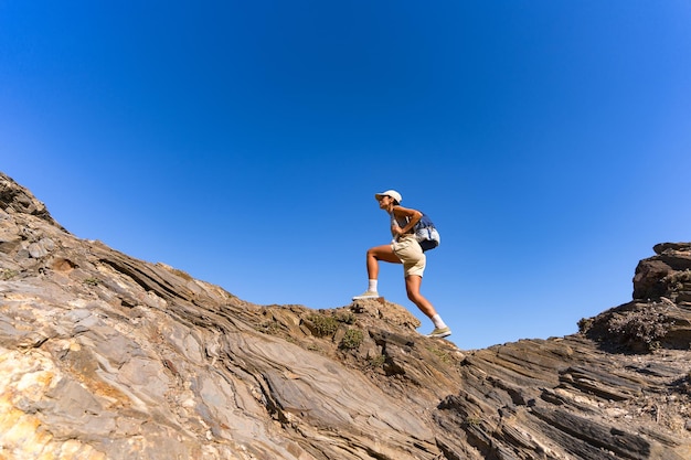 Foto una chica turista con una mochila en la espalda sube la montaña en verano