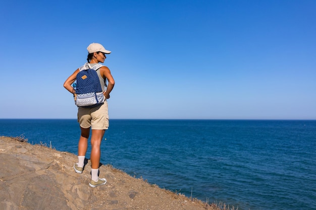 Foto una chica turista con una mochila en la espalda en el verano se encuentra en la cima de una montaña