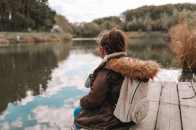 Foto chica turista se sienta en la orilla del río y disfruta de la hermosa vista
