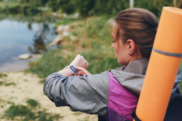 Una chica turista usa un reloj inteligente en una caminata Enfoque selectivo de la vista trasera