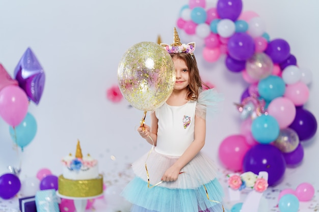 Chica unicornio con globo de oro confeti en fiesta de cumpleaños