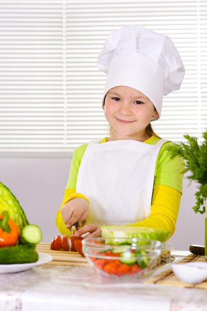 Chica con uniforme de chef cortando verduras