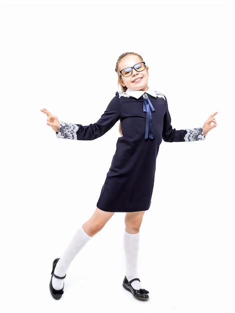 Chica en un uniforme escolar azul emocionalmente posando sobre un fondo blanco.