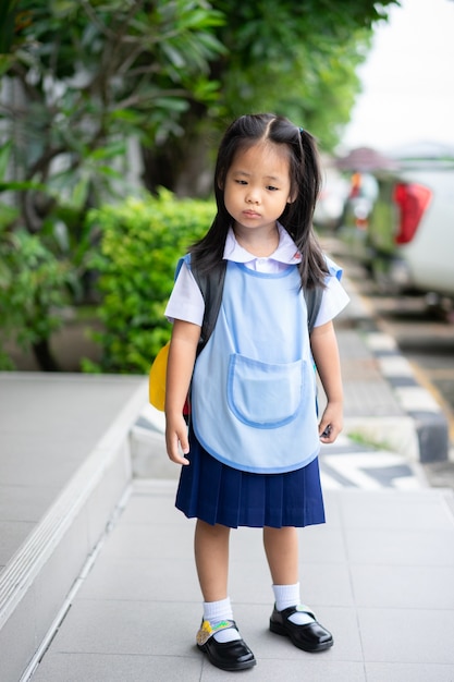 chica en uniforme escolar tailandés de pie en el parque, no lista para regresar a la escuela