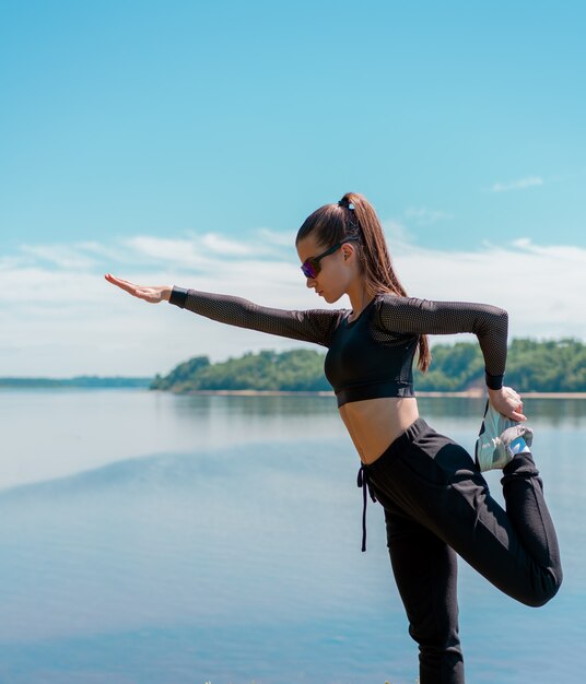 Chica en uniforme y gafas de sol haciendo deporte en un parque