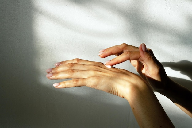 Chica se unta crema en la mano a la luz de la ventana