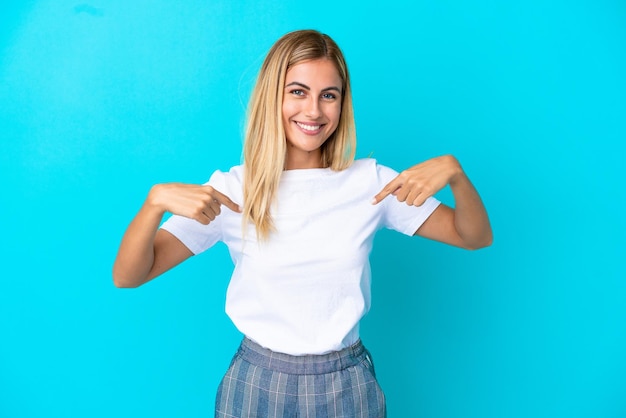 Chica uruguaya rubia aislada de fondo azul con expresión facial sorpresa