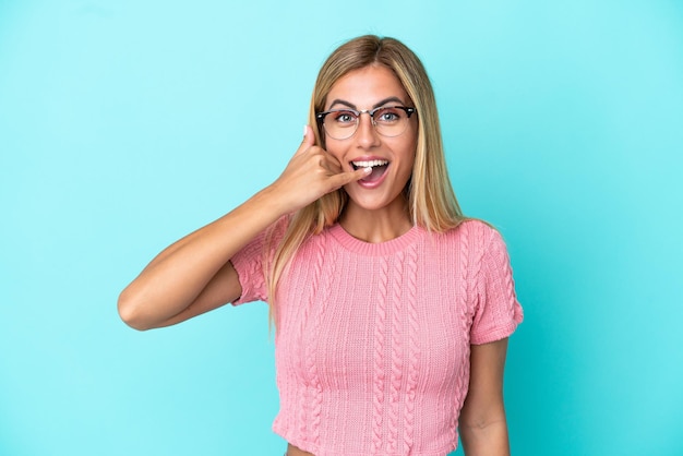 Chica uruguaya rubia aislada de fondo azul haciendo gestos telefónicos Llámame de nuevo