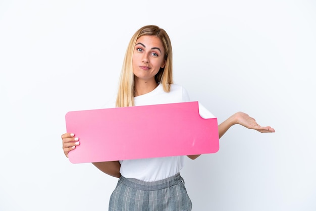 Chica uruguaya rubia aislada de fondo blanco sosteniendo un cartel vacío y teniendo dudas