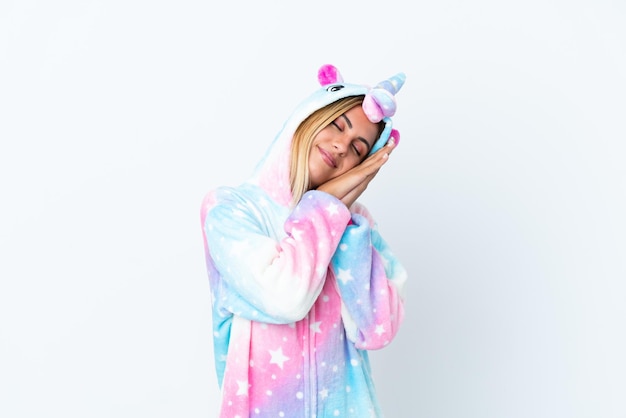 Foto chica uruguaya rubia con un pijama de unicornio aislado de fondo blanco haciendo gestos de sueño con una expresión adorable