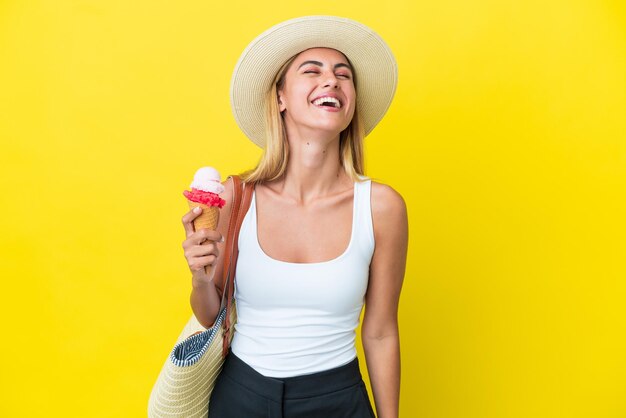 Chica uruguaya rubia en verano sosteniendo helado aislado sobre fondo amarillo riendo