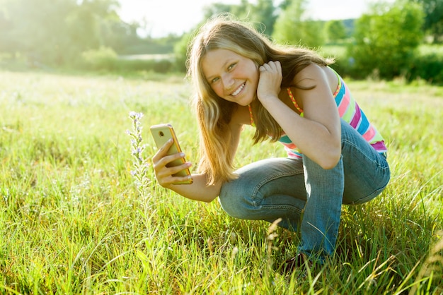 Chica usando teléfono inteligente, fotografiando flores