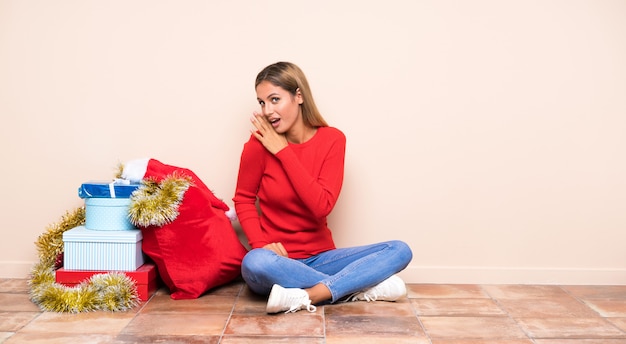 Chica en vacaciones de navidad sentada en el suelo susurrando algo